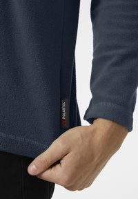Sudadera de forro polar azul marino con una textura suave, que presenta una etiqueta Polartec en el lateral y un puño y dobladillo bien cosidos.