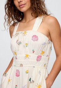 Vestido leve de cor creme com corpete franzido, alças largas e padrões coloridos de flores e conchas. Inclui bolsos laterais convenientes.