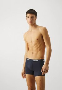 Temno modri bombažni bokser hlačke s širokim elastičnim pasom, na katerem je belo označena blagovna znamka "Levi's". Prilegajoč se kroj, gladka tekstura.