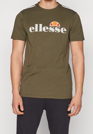 T-shirt vert olive à manches courtes avec le logo "ellesse" blanc et un détail en demi-cercle orange. Matériau en coton, design col rond, coupe régulière.