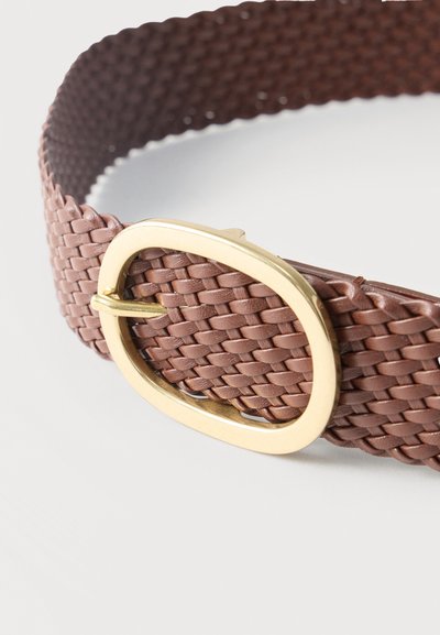 Καφέ πλεγτή δερμάτινη ζώνη με οβάλ χρυσή μεταλλική αγκράφα σε λευκό φόντο.
