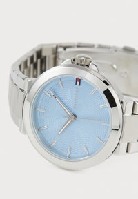 Silver stainless steel watch with a light blue textured dial, silver hour markers, and a polished bezel. Includes a metal link bracelet.
