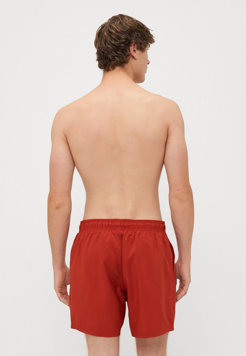 Costume da bagno rossi con vita regolabile, texture lucida e tasche laterali, visti da dietro su uno sfondo bianco semplice.
