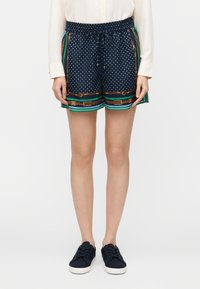 Calções de bolinhas azul-marinho com cintura elástica e cordão; apresentam padrão listrado colorido na bainha e detalhes em metal dourado.