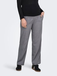 Pantalon gris léger à jambes larges avec une taille élastique et des poches latérales, associé à des chaussures de sport noires. Texture de tissu lisse.