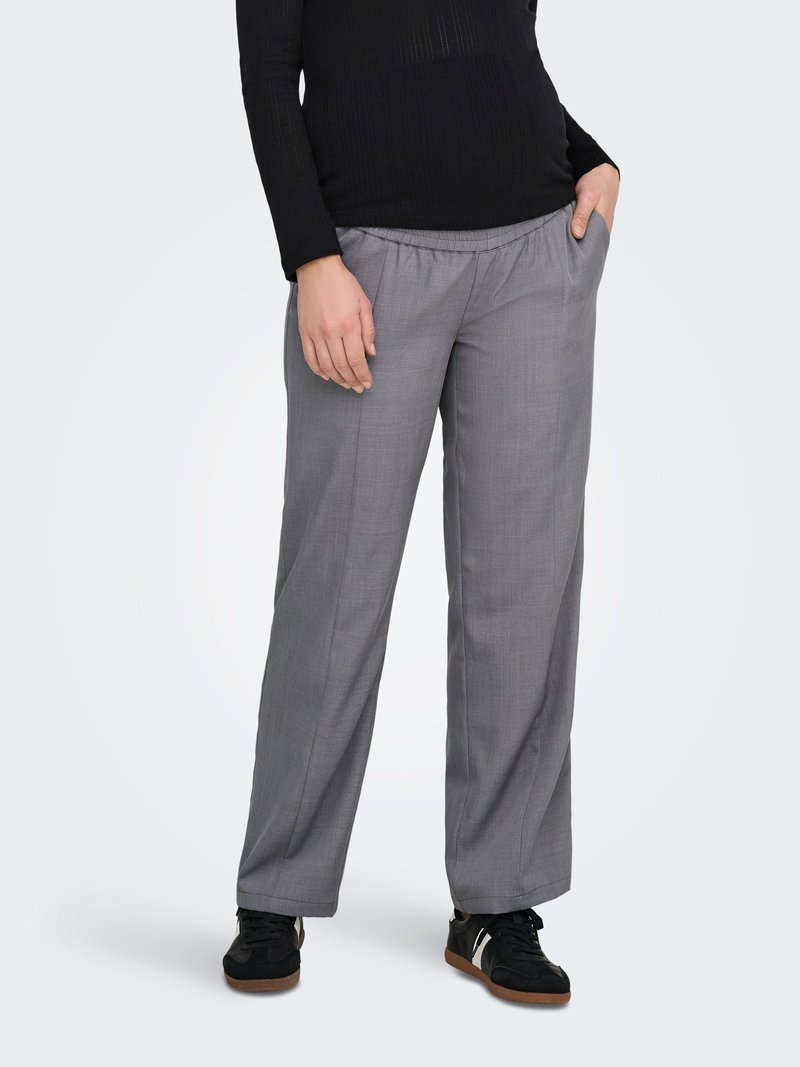 Pantalon gris léger à jambes larges avec une taille élastique et des poches latérales, associé à des chaussures de sport noires. Texture de tissu lisse.
