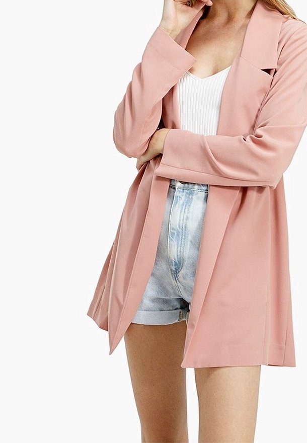 Blazer léger rose à manches longues et coupe décontractée, porté sur un top blanc à côtes et un short en denim. Texture lisse et sans fixations visibles.