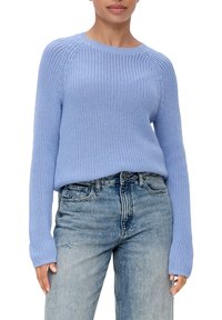 Jasnoniebieski sweter wykonany na drutach z okrągłym dekoltem, prążkowanymi mankietami i luźnym krojem, zestawiony z jeansami o wysokim stanie z efektami postarzenia.