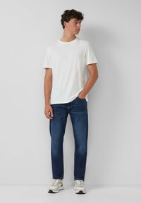 Witte t-shirt met korte mouwen, blauwe jeans en grijze sneakers. Glad materiaal, normale pasvorm en neutrale kleuren met minimale ontwerpelementen.