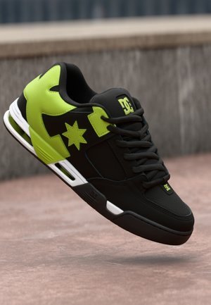 Black skate shoe featuring neon green accents and a star logo, with a padded collar, textured surface, and white sole details.