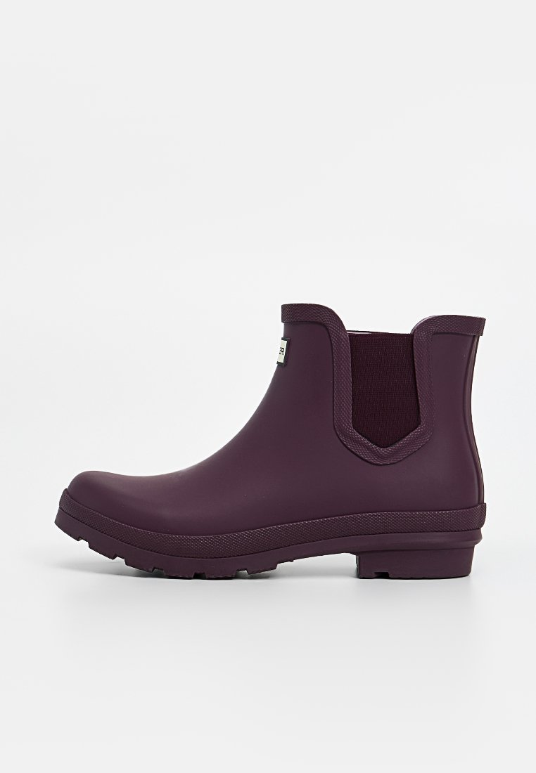 Botte de cheville en caoutchouc violet avec des panneaux latéraux élastiques, semelle texturée et finition lisse. Comprend une étiquette de logo sur le côté.