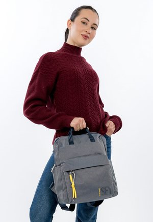 Grå mønstret rygsæk med letvægtsdesign, øverste håndtag og justerbare remme. Har gul lynlåstrækker og blå accenter.