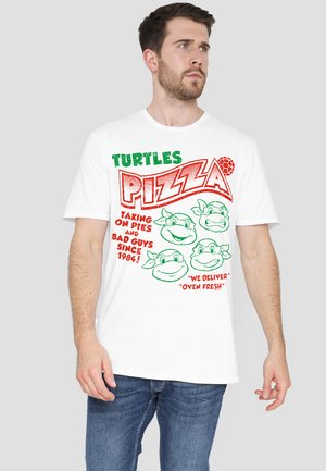 White cotton t-shirt featuring colorful graphics: "TURTLES PIZZA" in green and red, and cartoon turtle faces. Short sleeves, crew neck design.