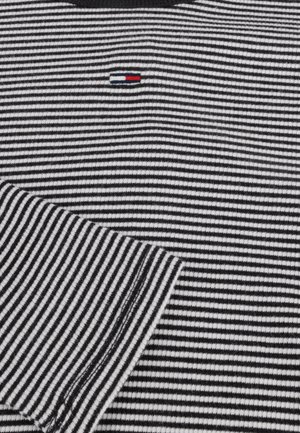 Black and white striped shirt featuring a small tri-color logo on the chest, ribbed collar, and smooth textured fabric.