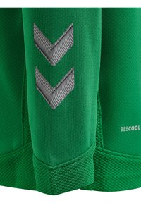 Grön sporttröja tillverkad av texturiserat tyg med zigzag-mönster i grått och 'BEECOOL'-logotypen på nedersta högra sidan. Har en tight passform.