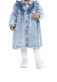 Denim-mekko, jossa on röyhelöpääntie, napitettava etuosa ja pitkät hihat. Yhdistetty valkoisiin polvipituisiin sukkiin ja valkoisiin tennareihin.