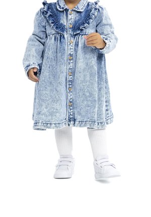 Denim-mekko, jossa on röyhelöpääntie, napitettava etuosa ja pitkät hihat. Yhdistetty valkoisiin polvipituisiin sukkiin ja valkoisiin tennareihin.