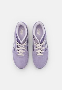 Fialové tenisky se semišovými a vzorovanými síťovanými panely, vybavené bílými tkaničkami a logem. Pozoruhodná kulatá špička a polstrované vložky.