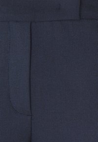 Granatowa tkanina o delikatnej prążkowanej fakturze, z boczną kieszenią i gładkim wykończeniem. Materiał wydaje się trwały i starannie wykonany.