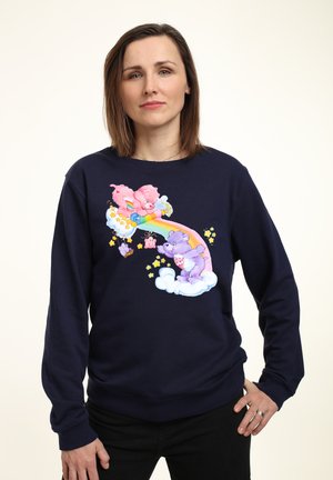 Marineblauwe sweatshirt met een kleurrijke cartoonafbeelding van roze en paarse beren op een regenboog met wolken en sterren. Zachte stof, relaxte pasvorm.