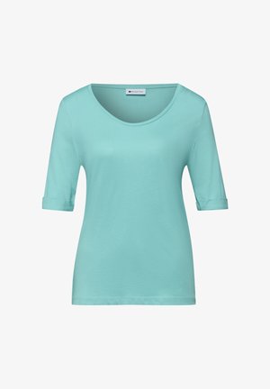 Camisa de mujer de manga corta azul claro con escote redondo y puños de manga doblados, mostrada sobre un fondo blanco.