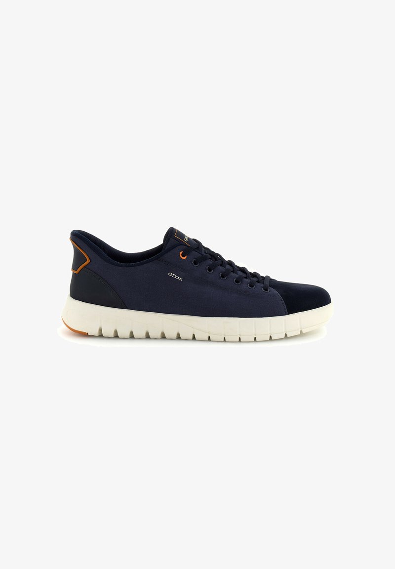 Baskets décontractées bleu marine avec semelle blanche rainurée, embout noir, accents orange et fermeture à lacets, positionnées sur un fond blanc.