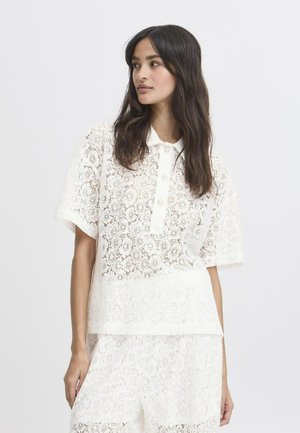 Witte kanten polo met een kraag en knoopsluiting, voorzien van een bloemenpatroon en korte mouwen. Lichtgewicht, semi-transparant materiaal.