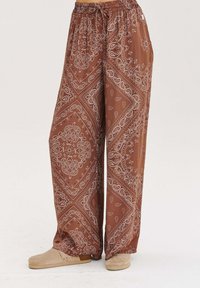 Zelené nohavice s širokými nohavicami a bielym paisley vzorom. Vyrobené z ľahkej textílie, majú elastický pás a uvoľnený strih.