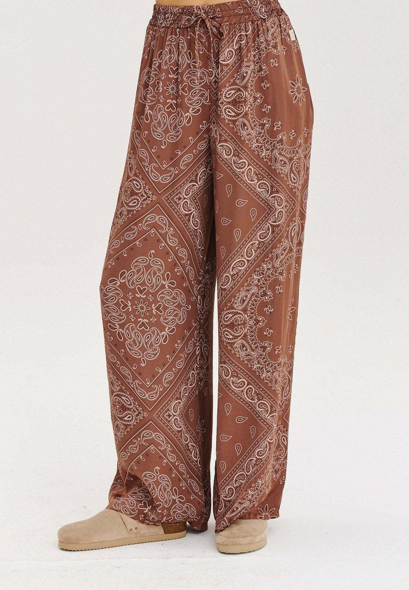 Zelené nohavice s širokými nohavicami a bielym paisley vzorom. Vyrobené z ľahkej textílie, majú elastický pás a uvoľnený strih.