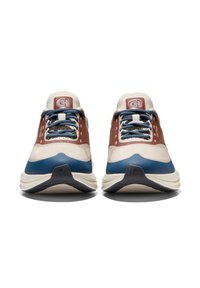 Ein Paar beiger, blauer und brauner Schnürsneaker, die nach vorne gerichtet auf einem weißen Hintergrund stehen, mit Sicht auf das Frontprofil und dem markierten Zungenpatch.