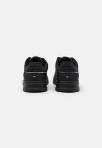 Baskets noires avec une finition en cuir lisse. Dotées d'un col et d'une languette rembourrés, d'accents texturés et du logo Tommy Hilfiger sur le talon.