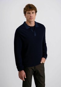 Marineblaues Langarm-Polohemd mit kontrastierendem Kragen, aus strukturiertem Stoff und in regulärer Passform, kombiniert mit dunklen Hosen.