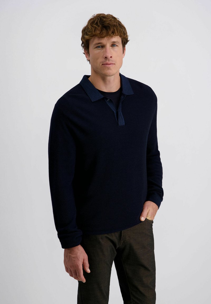 Marineblaues Langarm-Polohemd mit kontrastierendem Kragen, aus strukturiertem Stoff und in regulärer Passform, kombiniert mit dunklen Hosen.