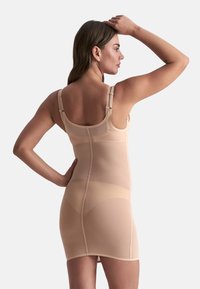 Abito shapewear in nude, realizzato in rete elastica con spalline regolabili, texture morbida, design aderente e lunghezza fino a metà coscia.