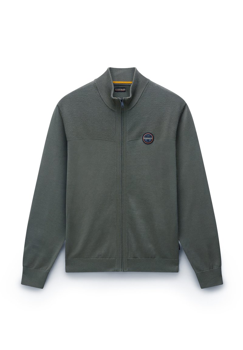Veste zippée vert olive avec un panneau supérieur texturé, col montant, poignets côtelés et un logo circulaire sur la poitrine gauche. Tissu lisse.