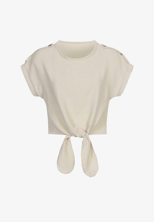 Camiseta corta de color beige claro, fabricada con un tejido suave. Presenta mangas cortas enrolladas y un detalle de nudo atado en la parte frontal.