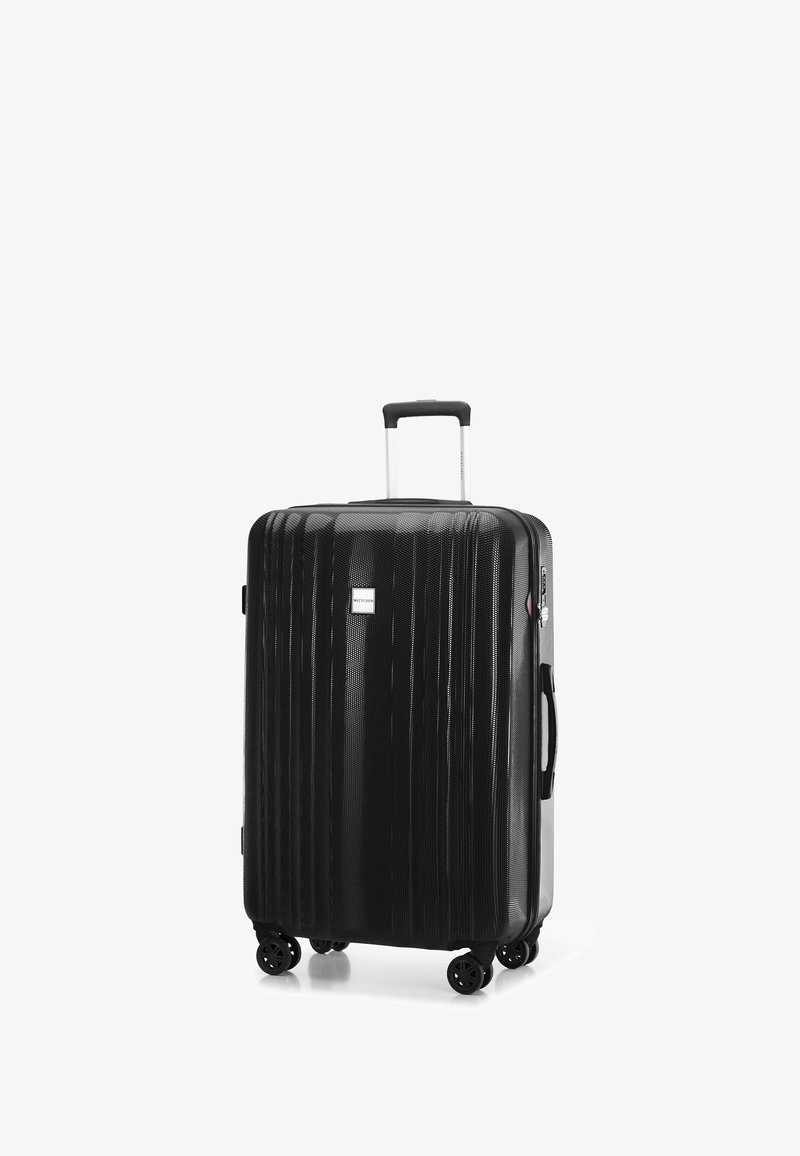 Zwarte harde koffer met verticale ribbels, uitschuifbare handgreep en vier draaiwielen. Voorzien van een klein logo en een zijhandgreep.