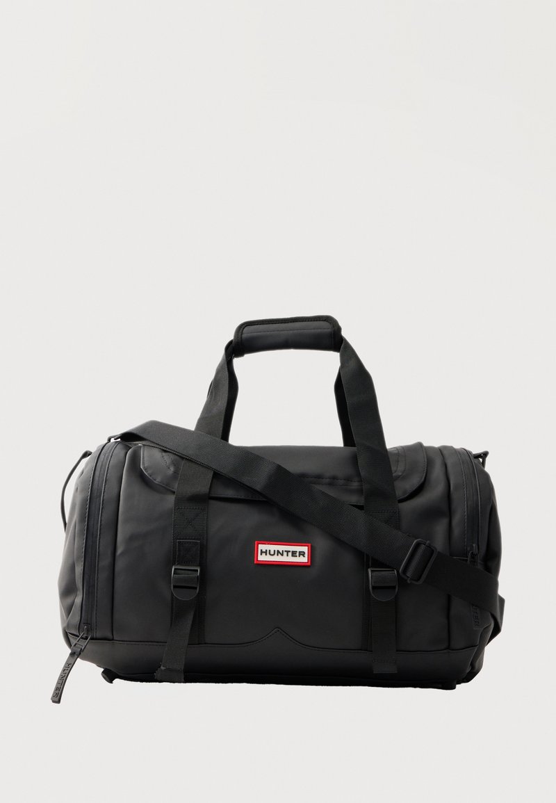 Μαύρο σακίδιο Black Hunter με δύο λαβές, ρυθμιζόμενο ιμάντα ώμου και πατσακι λογότυπου μπροστά, παρουσιάζεται σε απλό φωτεινό φόντο.