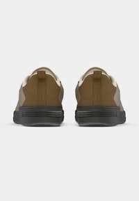 Barna sportcipők texturált felsőrésszel és kontrasztos világos szegéllyel. Tartós talppal és húzófülekkel a saroknál.