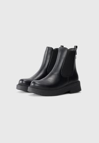Cizme negre până la gleznă, cu un finisaj din piele netedă, panouri laterale elastice și o talpă chunky din cauciuc. Design minimalist, fără elemente metalice sau modele vizibile.