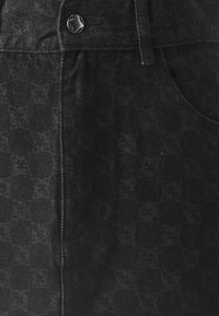 Svart denimstoff med en subtil tekstur og mønster, med en stjernesformet knapp og klassisk lommeutseende.