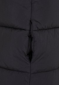 Doudoune noire avec un design matelassé, dotée d'une fermeture éclair et de deux poches latérales. Le matériau semble lisse et isolé.