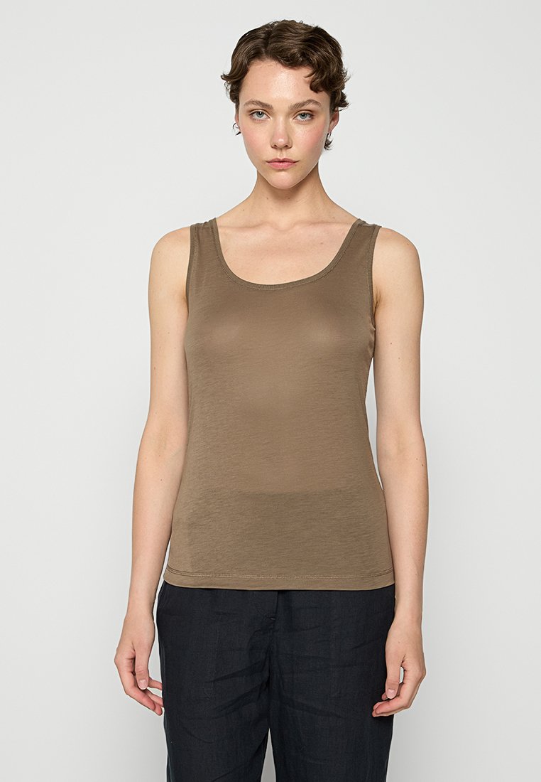 Brązowy top na ramiączkach z okrągłym dekoltem, bez rękawów, gładką strukturą i dopasowanym fasonem. W połączeniu z luźnymi ciemnymi spodniami.