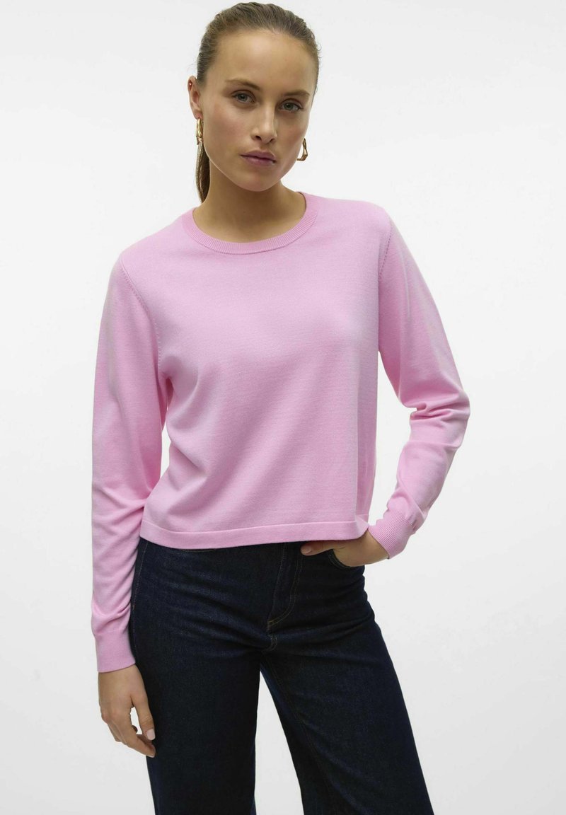 Felpa a maniche lunghe rosa chiaro con scollo rotondo, dal fit rilassato e polsini a costine, abbinata a jeans in denim scuro. Texture liscia.