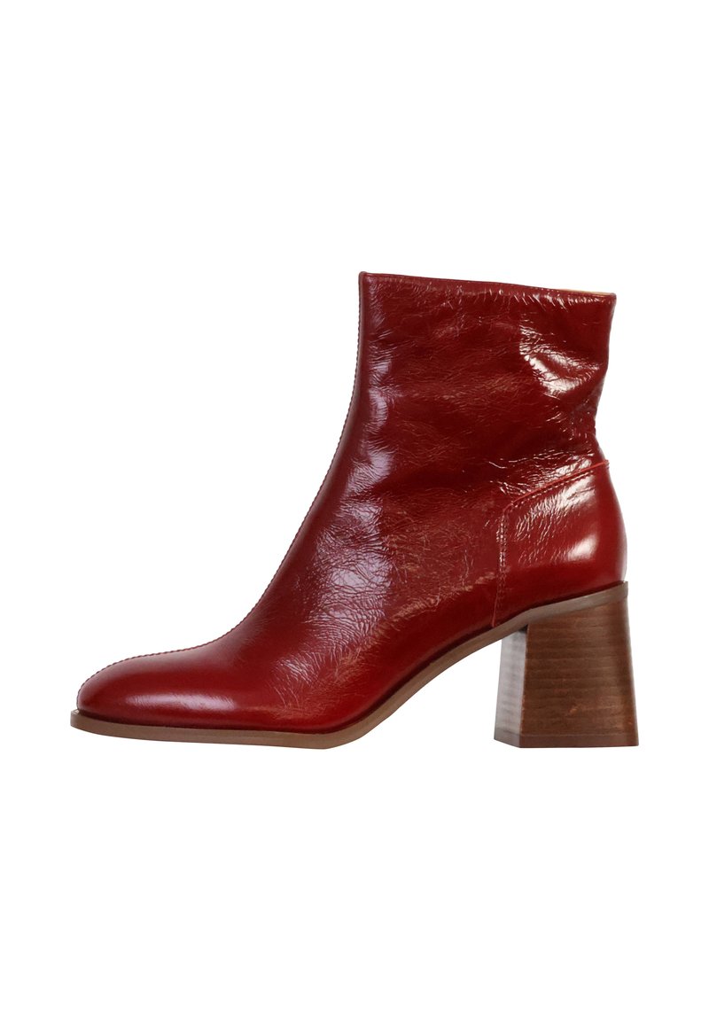 Botín de cuero rojo hasta el tobillo con punta afilada, acabado texturizado y tacón de madera gruesa. Presenta un caña ajustada y un diseño minimalista.