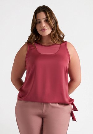 Roze mouwloos topje met een ronde hals en een uitsnijding, gemaakt van soepel materiaal. Heeft een gestrikte accent bij de heup.