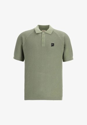 Šviesiai žalia polo marškinėliai su tekstūruota mezgimo struktūra, trumpomis rankovėmis ir trimis mygtukais. Krūtinėje yra juodas logotipo ženklelis.