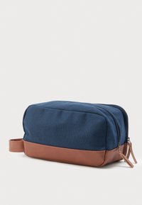 Ορθογώνια τσάντα καλλωπισμού σε ναυτικό μπλε και καφέ χρώμα, με διπλούς φερμουάρ και πλαϊνή θηλιά μεταφοράς, σε λευκό φόντο.