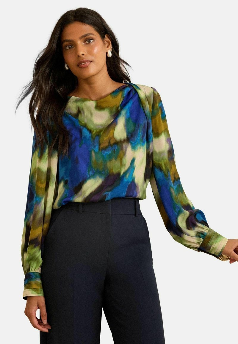 Színes, lebegő blúz, élénk absztrakt mintával zöld, kék és krémszínben, hosszú ujjal és laza fazonnal.