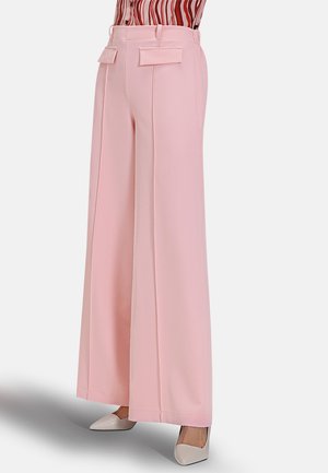 Pantaloni palazzo rosa con due tasche a toppa frontali, design sartoriale e tessuto dalla texture liscia, abbinati a décolleté di colore chiaro.